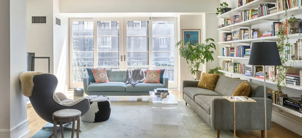 Bright living room with modern furniture, bookshelves, and large windows.